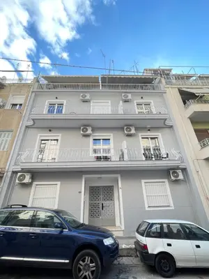 a building with two cars parked in front of it at Uoohome7 garden green and navy in Athens