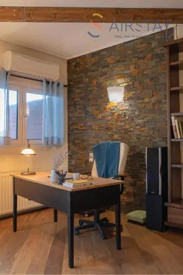 an office with a desk and a chair and a brick wall at Kalista apartment Airport by Airstay in Spáta