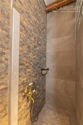 a bathroom with a shower with a stone wall at Kalista apartment Airport by Airstay in Spáta