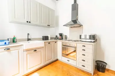 a kitchen with white cabinets and a sink and a stove at Oasis Architect's Dream Neoclassical House next to Acropolis in Athens