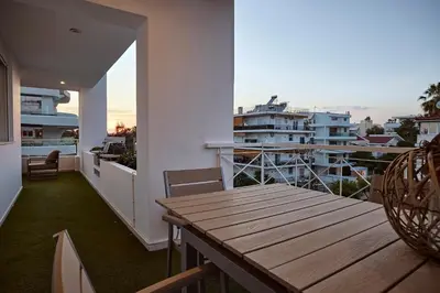 a balcony with a wooden table and chairs and buildings at Elaia Luxury Selections Opal in Athens