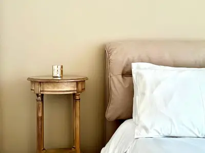a nightstand next to a bed with a cup on it at Elaia Luxury Selections Opal in Athens