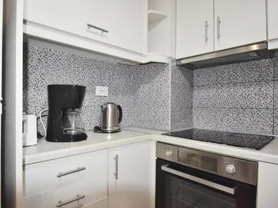 a kitchen with white cabinets and a black appliance at Petite Apartment in Athens