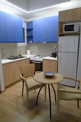 a kitchen with blue cabinets and a table and chairs at Nice 1BD apartment close to metro station Ampelokipoi in Athens