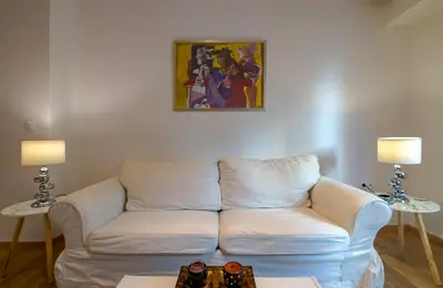 a living room with a white couch and two lamps at Nice 1BD apartment close to metro station Ampelokipoi in Athens