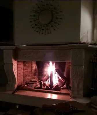 a fireplace with a fire in it with a clock at Poseidonio in Piraeus