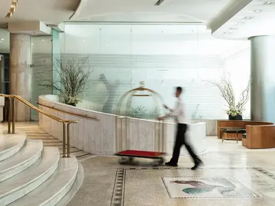 a man pushing a luggage cart in a lobby at Titania Hotel in Athens