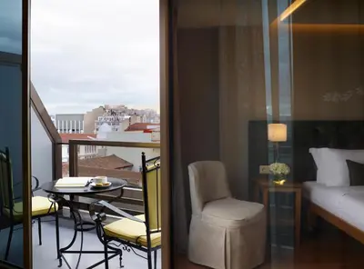 a room with a balcony with a table and a bed at Titania Hotel in Athens