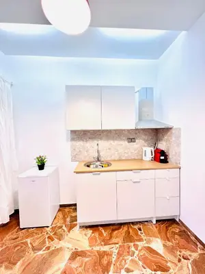 a kitchen with white cabinets and a wooden floor at sky inn with wonderful Acropolis view in Neos kosmos in Athens
