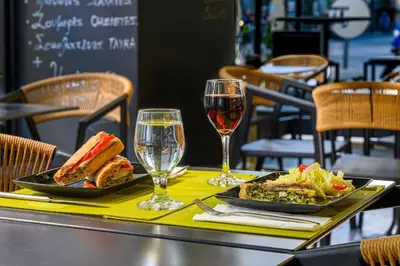 a table with two plates of food and glasses of wine at Polis Grand Hotel in Athens