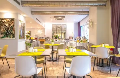 a restaurant with yellow tables and chairs at Polis Grand Hotel in Athens