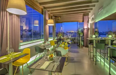 a restaurant with tables and chairs and large windows at Polis Grand Hotel in Athens