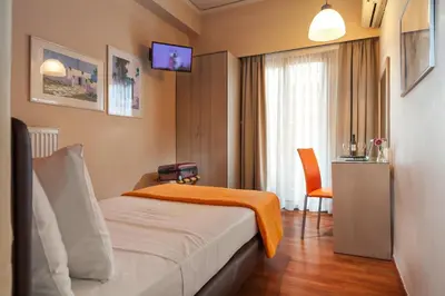 a hotel room with a bed with an orange blanket on it at Lilia Hotel in Piraeus