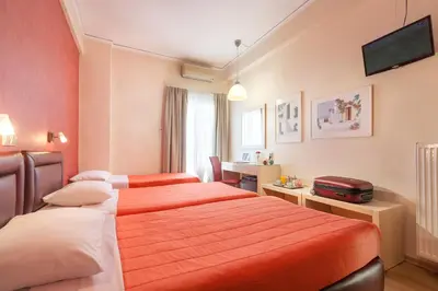 a hotel room with two beds and a desk at Lilia Hotel in Piraeus