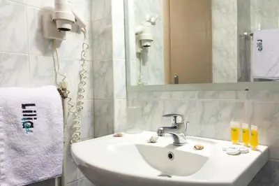 a bathroom with a white sink and a mirror at Lilia Hotel in Piraeus