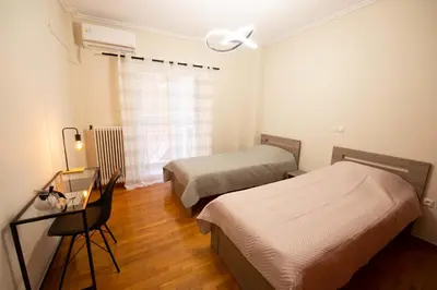 a bedroom with two beds and a desk and a window at DIMANTHEO in Athens