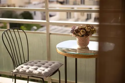 a table with a vase of flowers and a chair at DIMANTHEO in Athens