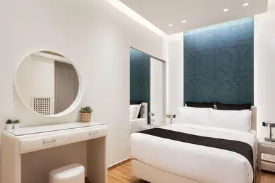 a white bedroom with a bed and a mirror at Acropolis Prestige Residence in Athens