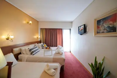 a hotel room with two beds and a window at Crystal City Hotel in Athens