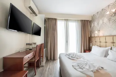 a hotel room with a bed and a desk and a television at Athens Golden City Hotel in Athens