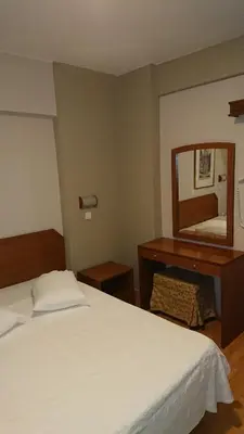 a bedroom with a bed and a dresser and a mirror at Economy Hotel in Athens