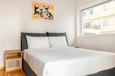 a bedroom with a white bed and a window at Skiathou 12 Contemporary Residences in Athens