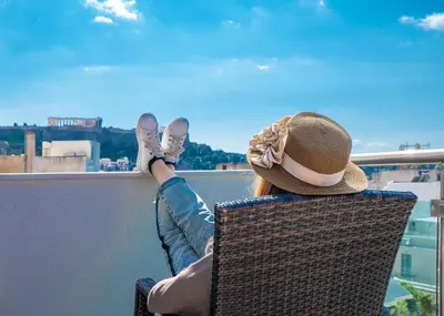 a person sitting in a chair with their feet up on a balcony at Attalos Hotel in Athens