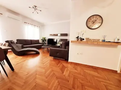 a living room with a couch and a clock on the wall at Lovely 2-Bedroom 4th Floor House Large Patio in Athens