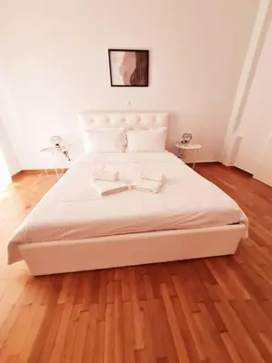 a large white bed in a room with a wooden floor at Lovely 2-Bedroom 4th Floor House Large Patio in Athens