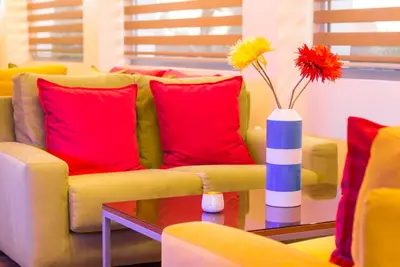 a yellow couch with red pillows and a vase with flowers at Tropical Hotel in Athens