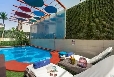 a swimming pool with a table and chairs next to it at Tropical Hotel in Athens