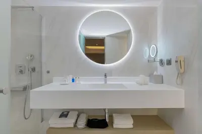a white bathroom with a sink and a mirror at Radisson Blu Park Hotel Athens in Athens