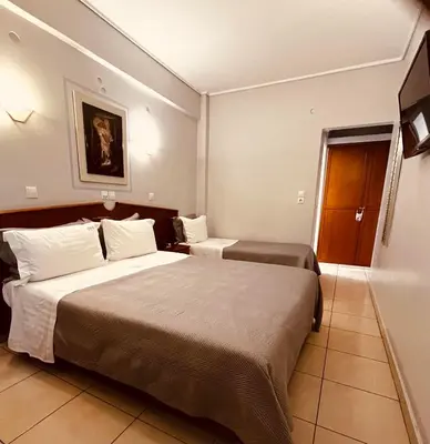 a hotel room with two beds and a television at Triton Hotel Piraeus in Piraeus