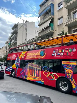 a red double decker bus driving down a street at Acropolis selected apartment in Athens
