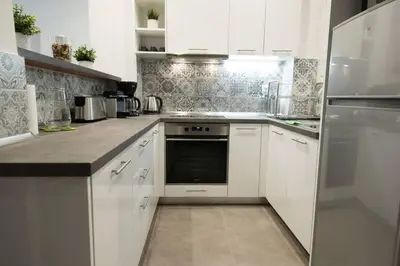 a white kitchen with white cabinets and a refrigerator at Acropolis selected apartment in Athens