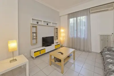 a living room with a couch and a tv and a table at Mavili Square Cozy Apt AC & Kitchen, near Metro in Athens