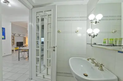 a white bathroom with a sink and a mirror at Mavili Square Cozy Apt AC & Kitchen, near Metro in Athens