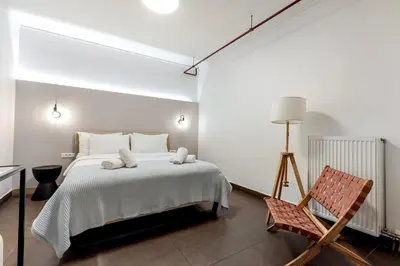 a bedroom with a bed and a chair at Filopapou Pearl on Acropolis Hill in Athens