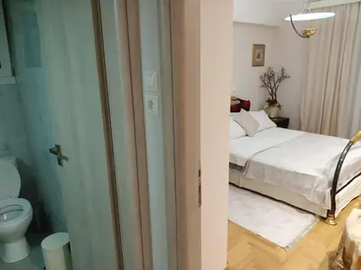 a bathroom with a bed and a toilet in a room at Renovated Basement Duplex with Patio and Folk Decor in the Heart of Athens in Athens