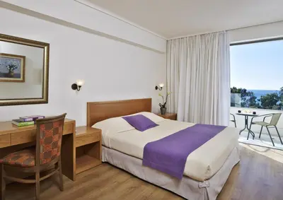a hotel room with a bed and a desk and a window at Amarilia Hotel in Athens