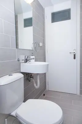 a bathroom with a toilet and a sink and a mirror at Sunny and minimal apt in Glyfada with 3 bdrm in Athens