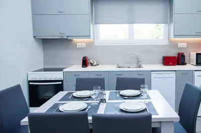 a kitchen with a table with plates and glasses on it at Sunny and minimal apt in Glyfada with 3 bdrm in Athens