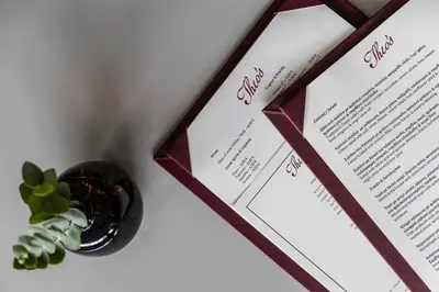 a table with two wedding diplomas and a vase of plants at Amalia Hotel Athens in Athens