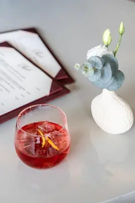 a drink in a bowl next to a vase with flowers at Amalia Hotel Athens in Athens
