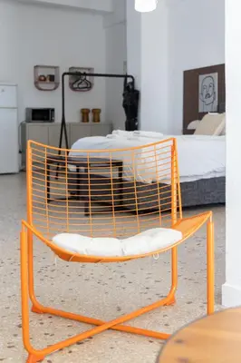 a orange chair with a table in a room at Loft at historical center of Athens Acropolis View in Athens
