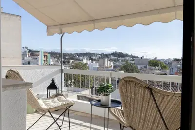 a balcony with two chairs and a table and an umbrella at Loft at historical center of Athens Acropolis View in Athens