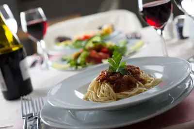 a plate of pasta on a table with wine glasses at Delphi Art Hotel by Prima Hotels in Athens