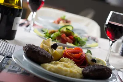 a plate of food on a table with a glass of wine at Delphi Art Hotel by Prima Hotels in Athens