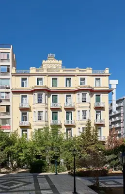 a large tan building with trees in front of it at Delphi Art Hotel by Prima Hotels in Athens
