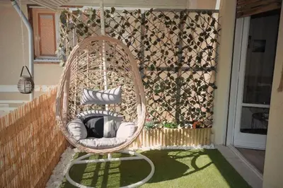 a wicker chair sitting on the side of a porch at Cozy Apartment in the heart of Athens! in Athens